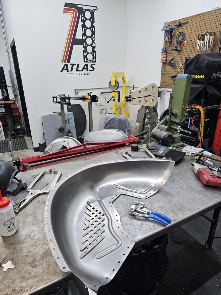Hand-built mini tub with bead-rolled ribs and dimple-die braces on the bench, Atlas Speed Co. logo on the shop wall