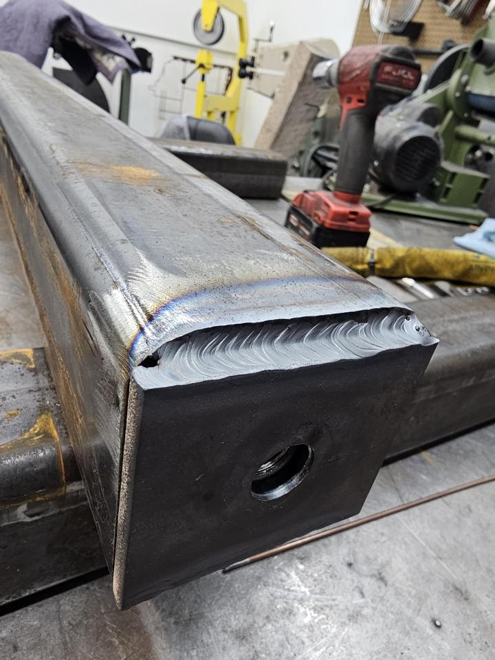 Boxed steel frame rail end with a capped plate and full weld bead