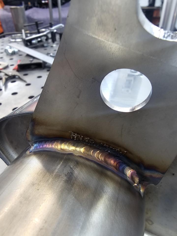 Close-up of a TIG weld joining a stainless hanger bracket to exhaust tubing
